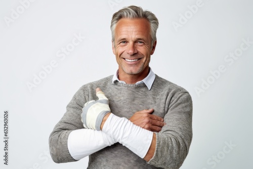Medium shot portrait photography of a man in his 50s wearing a wrist brace because of a minor sprain wearing a chic cardigan against a white background 