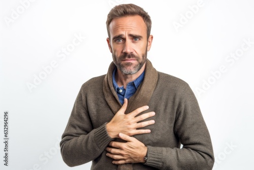 Medium shot portrait photography of a man in his 30s clutching his chest due to gastroesophageal reflux disease wearing a cozy sweater against a white background 