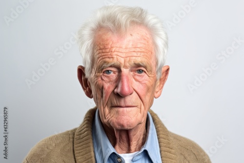 Medium shot portrait photography of a man in his 80s with furrowed brows and a tense expression due to hypertension wearing a chic cardigan against a white background 