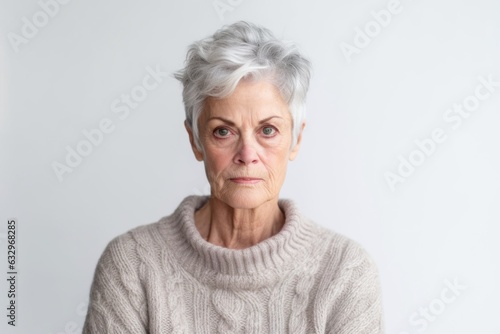 Medium shot portrait photography of a woman in her 60s appearing weakened and pale because of anemia wearing a cozy sweater against a white background 