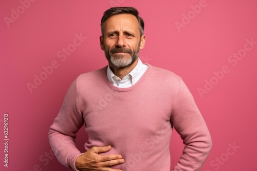 Obraz na płótnie Medium shot portrait photography of a man in his 40s holding his stomach with discomfort from gastritis wearing a chic cardigan against a pastel or soft colors background w salonie