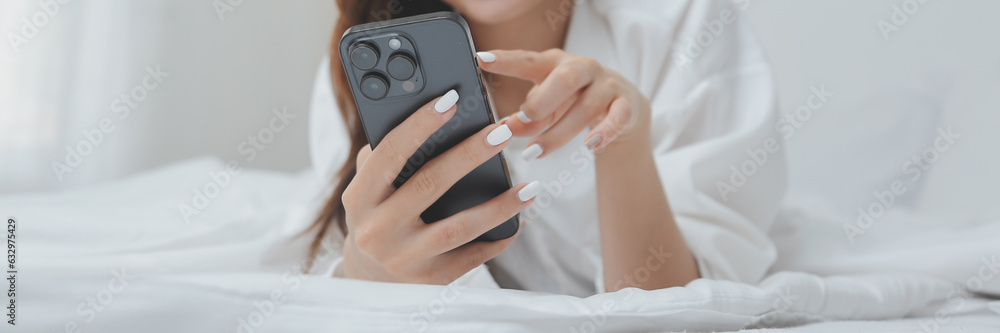 Happy young female in casual clothes smiling and looking at camera while using laptop on bed in bedroom at home Happy young female in casual clothes smiling and looking at camera while using laptop on bed in bedroom at home