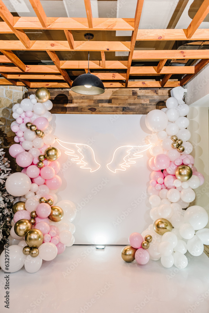Arch decorated with pink, white and golden balloons, angel wings. Copy