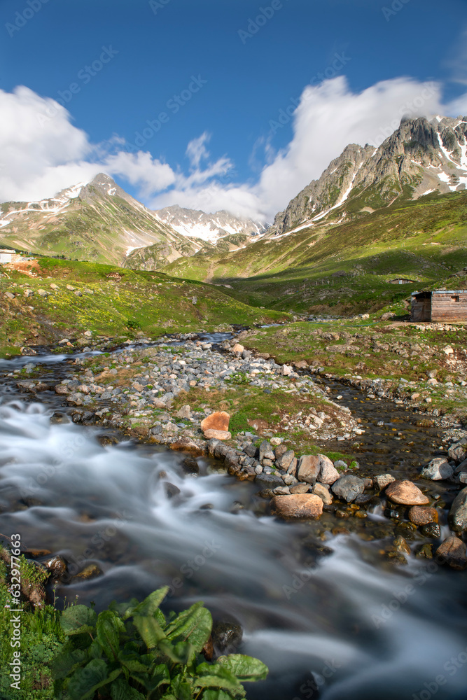 Cloudy mountains, stream formed by snow waters. Snowy and cloudy mountains. Mountain and stream landscape taken with long exposure. Ovuser plateau, Rize Türkiye.