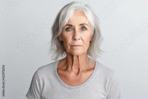 Medium shot portrait photography of a woman in her 50s with a somber and deeply sad expression due to major depression wearing a casual t-shirt against a white background 