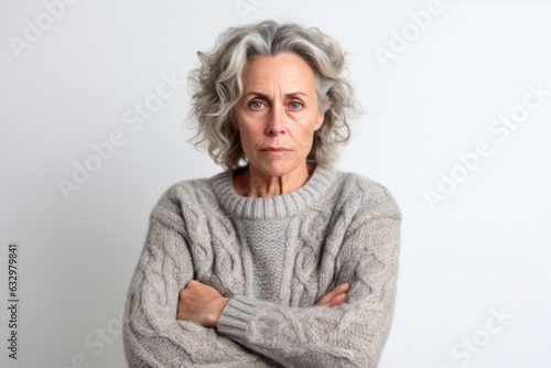 Medium shot portrait photography of a woman in her 50s looking anxious and fidgety due to generalized anxiety disorder wearing a cozy sweater against a white background 