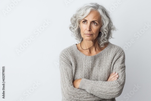 Group portrait photography of a woman in her 50s looking anxious and fidgety due to generalized anxiety disorder wearing a cozy sweater against a white background 