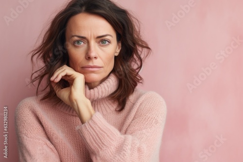 Lifestyle portrait photography of a woman in her 40s looking anxious and fidgety due to generalized anxiety disorder wearing a cozy sweater against a pastel or soft colors background 