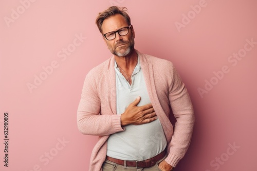 Medium shot portrait photography of a man in his 40s clutching his abdomen due to irritable bowel syndrome wearing a chic cardigan against a pastel or soft colors background 