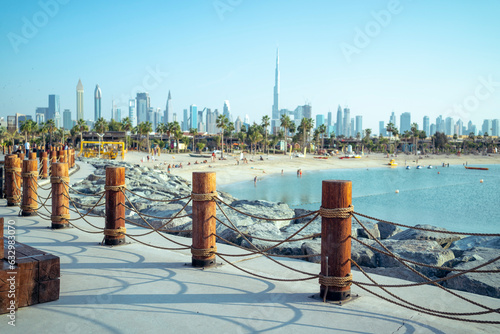 Wallpaper Mural The wooden pillars of Dubai's La Mer beach, people are relaxing, the skyscrapers of the city are out of focus in the distance. United Arab Emirates Torontodigital.ca