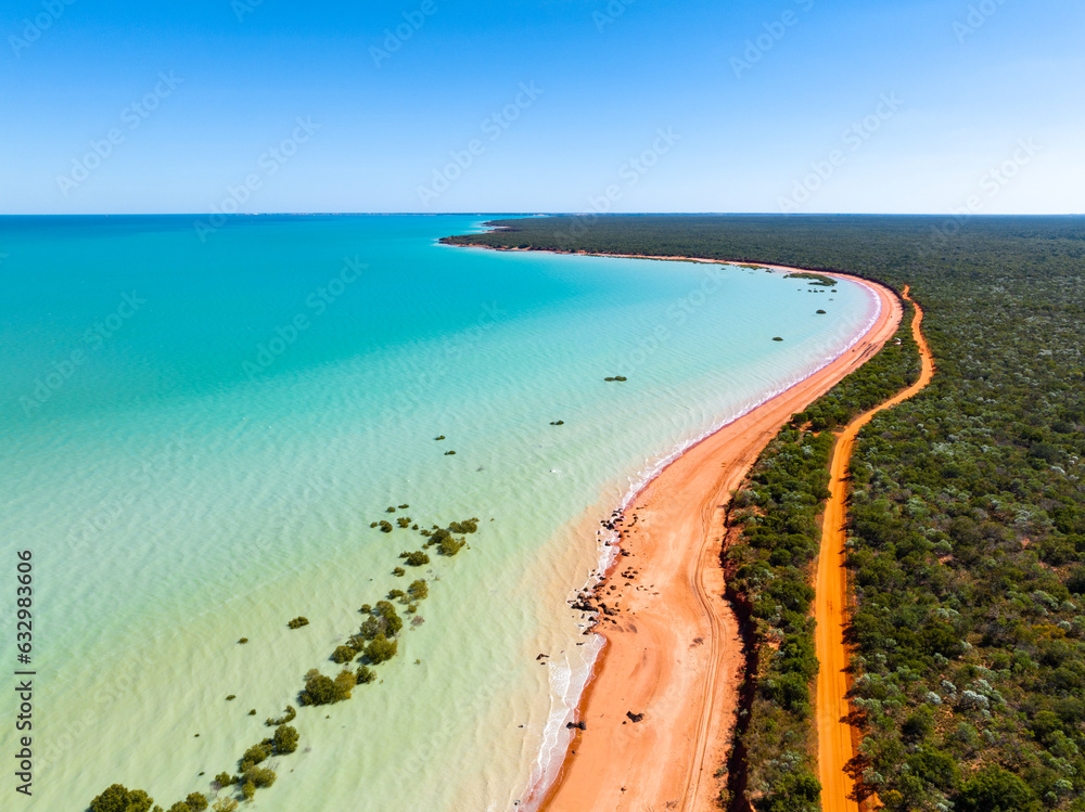 Aerial view of red sandy coastline along turquoise water at Red Sand Beach, Roebuck Bay, Broome, Western Australia