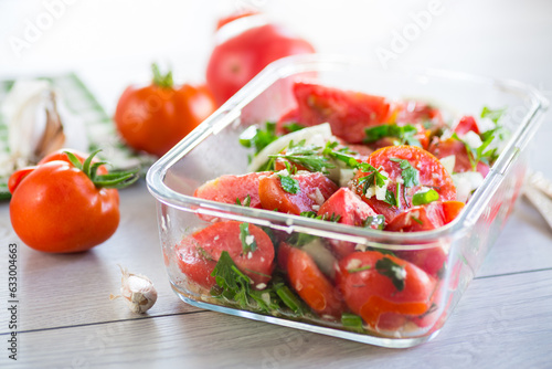 Spicy snack tomatoes with garlic  herbs  seasonings and onions in a glass bowl .