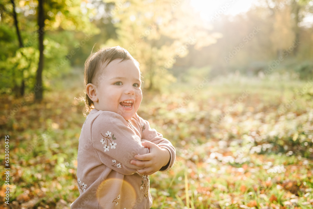 Child playing in park. Little girl walking in autumn leaves in forest. Family with kid spending time together at sunset on vacation. Autumn holiday in nature. Closeup. Spring mood photo with sunlight Child playing in park. Little girl walking in autumn leaves in forest. Family with kid spending time together at sunset on vacation. Autumn holiday in nature. Closeup. Spring mood photo with sunlight
