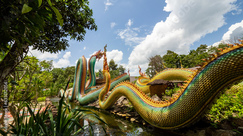 Ubon Ratchathani, THAILAND - August 8, 2023: Buddhist travel glowing serpent statue with sunlight at Wat Pa Phu pang temple, Si Chiang Mai District, Ubon Ratchathani Province, Thailand. photo