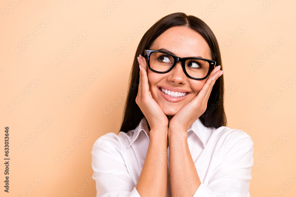Portrait of minded creative gorgeous lady beaming smile arms touch cheekbones look empty space isolated on beige color background Portrait of minded creative gorgeous lady beaming smile arms touch cheekbones look empty space isolated on beige color background