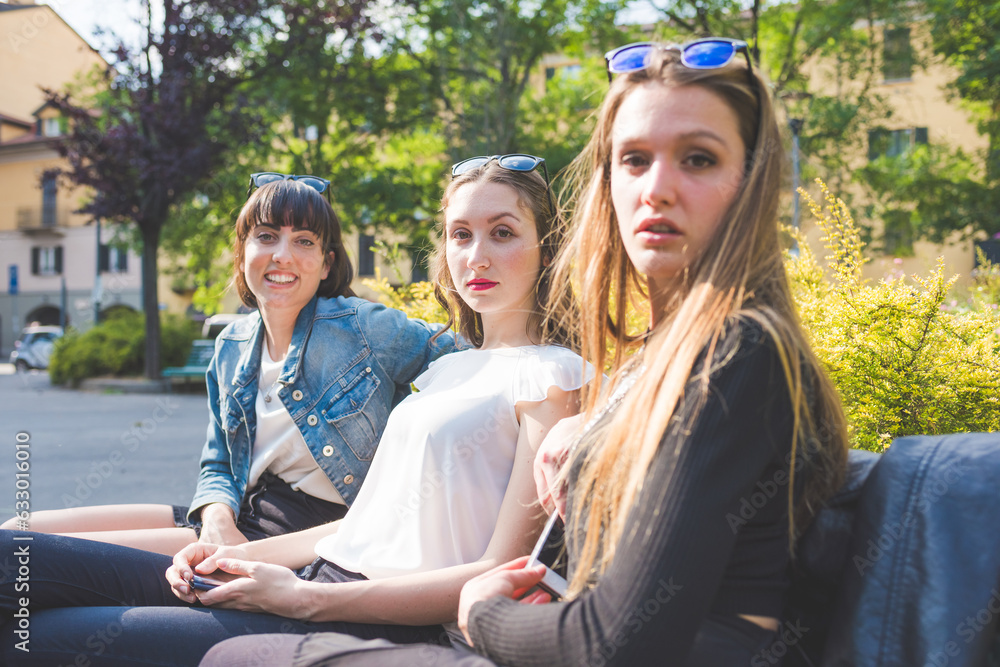 Three young happy women friends posing outdoors having fun