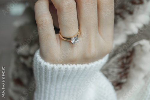 Close up of diamond ring on woman’s finger. Love, valentine, relationship and wedding concept. Soft and selective focus.