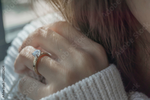 Close up of diamond ring on woman’s finger with sunlight and shadow. Love, valentine, relationship and wedding concept. Soft and selective focus.