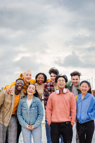 Vertical portrait of a big goup of multiracial teenage highschool students having fun,smiling and laughing together. Young cool best friends cheering and enjoying a social gathering staring front
