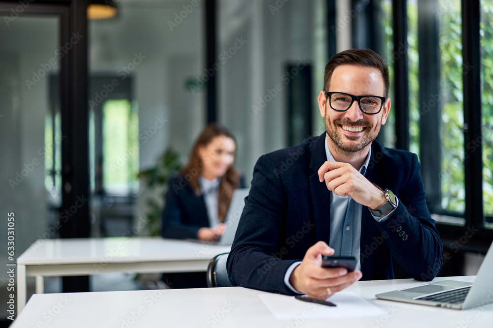 © bnenin - Portrait of a businessman with glasses on sitting at the office, holding a mobile phone. © bnenin - Portrait of a businessman with glasses on sitting at the office, holding a mobile phone.
