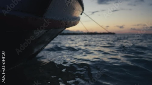 Beautiful sea water splashing on fishing boat. Ripples of ocean and fishermans vessel at sunset. Seascape with grey waves under pink sky. Blue color Island coast in twilight . Sunrise in open sea. photo