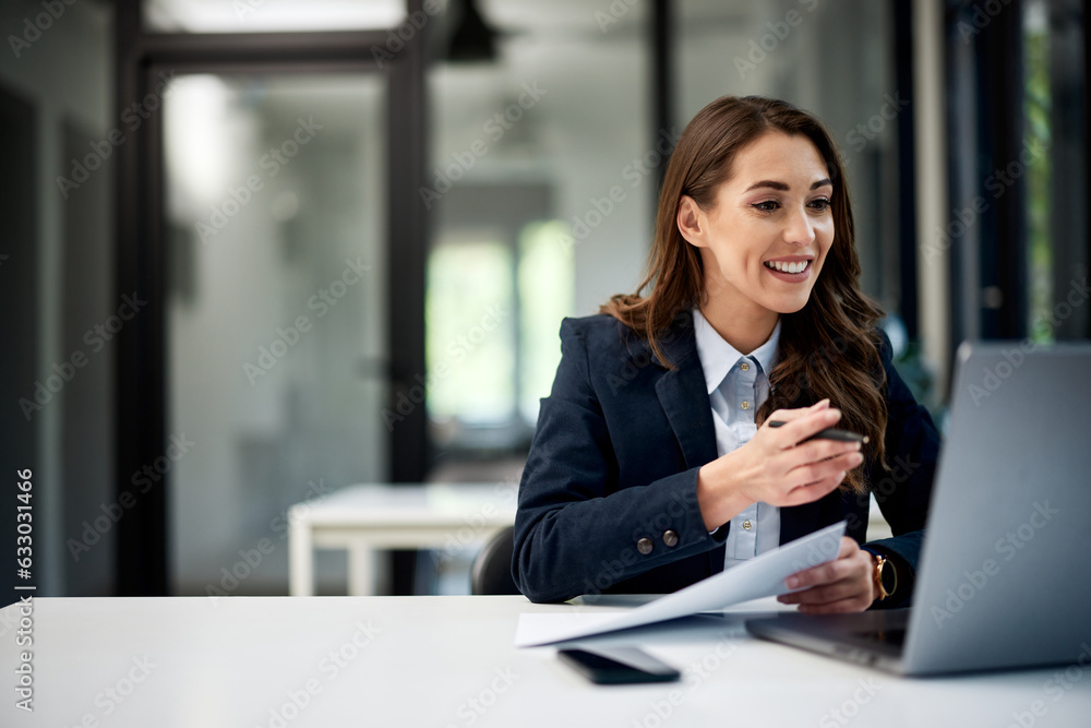 A smiling businesswoman holding paper and having an online meeting over a laptop. A smiling businesswoman holding paper and having an online meeting over a laptop.