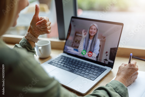 Close up of woman freelancer have video conference with client and making notes sitting near window