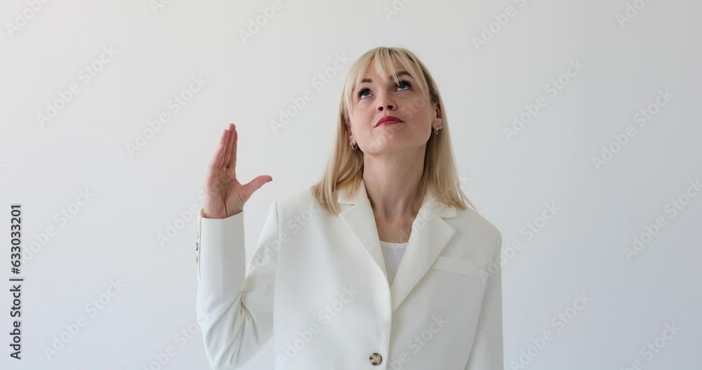 Unsatisfied woman is seen on a clean white backdrop, expressing her dissatisfaction with a blah blah gesture by moving her hand horizontally near her mouth. Unsatisfied woman is seen on a clean white backdrop, expressing her dissatisfaction with a blah blah gesture by moving her hand horizontally near her mouth.