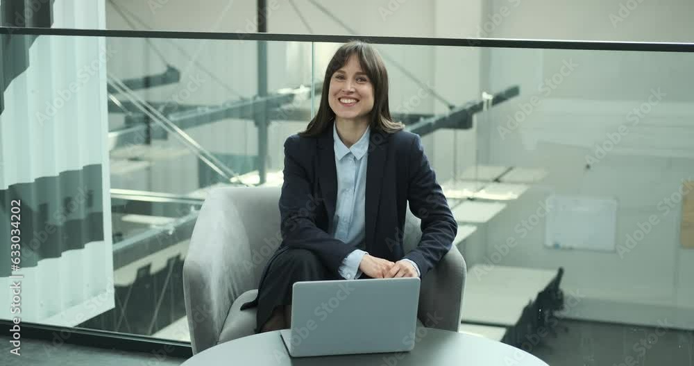 Cheerful female entrepreneur as she sits comfortably in a chair with her laptop, looking directly at the camera with a warm smile. Her positive energy radiates through her expression. Cheerful female entrepreneur as she sits comfortably in a chair with her laptop, looking directly at the camera with a warm smile. Her positive energy radiates through her expression.