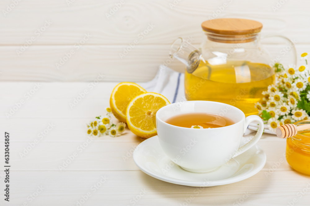 Chamomile tea on a white table. Delicious tonic, soothing and relaxing chamomile tea with chamomile flowers, honey and lemon. Herbal tea for immunity. Close-up.Place for text.Copy space. Chamomile tea on a white table. Delicious tonic, soothing and relaxing chamomile tea with chamomile flowers, honey and lemon. Herbal tea for immunity. Close-up.Place for text.Copy space.