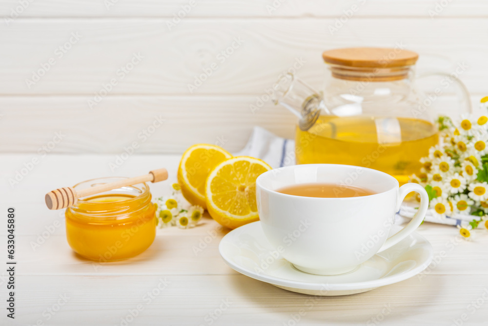 Chamomile tea on a white table. Delicious tonic, soothing and relaxing chamomile tea with chamomile flowers, honey and lemon. Herbal tea for immunity. Close-up.Place for text.Copy space. Chamomile tea on a white table. Delicious tonic, soothing and relaxing chamomile tea with chamomile flowers, honey and lemon. Herbal tea for immunity. Close-up.Place for text.Copy space.