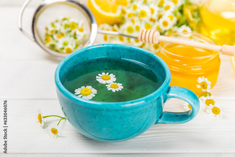 Chamomile tea on a white table. Delicious tonic, soothing and relaxing chamomile tea with chamomile flowers, honey and lemon. Herbal tea for immunity. Close-up.Place for text.Copy space. Chamomile tea on a white table. Delicious tonic, soothing and relaxing chamomile tea with chamomile flowers, honey and lemon. Herbal tea for immunity. Close-up.Place for text.Copy space.