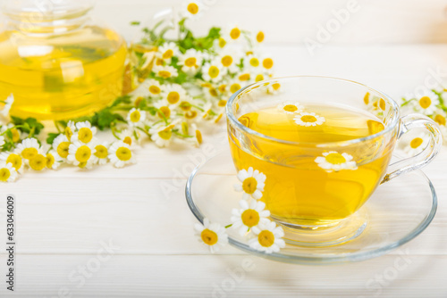 Chamomile tea on a white table. Delicious tonic, soothing and relaxing chamomile tea with chamomile flowers, honey and lemon. Herbal tea for immunity. Close-up.Place for text.Copy space.