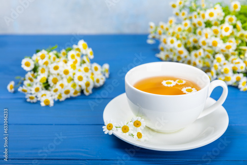 Chamomile tea on a blue table. Delicious tonic, soothing and relaxing chamomile tea with chamomile flowers, honey and lemon. Herbal tea for immunity. Close-up.Place for text.Copy space.