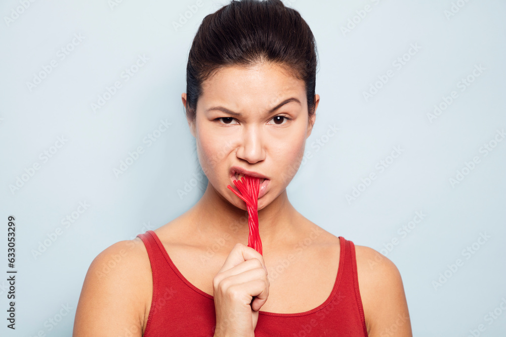 Young woman eating red liquorice Young woman eating red liquorice