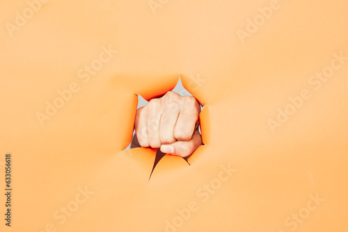 Hand punching through cutout in paper