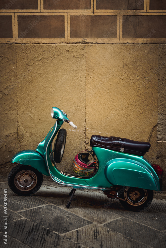 Vintage green Vespa parked gracefully in front of a charming building in Arezzo, Italy