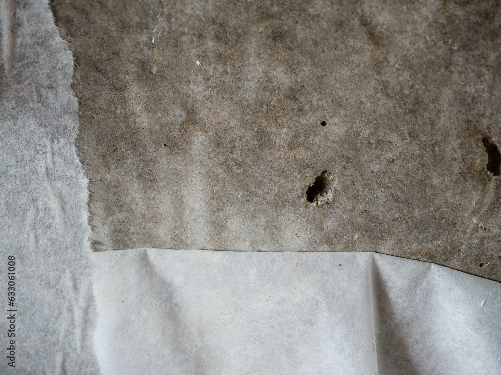 Old paper wallpaper hangs from a concrete wall. Old walls. Old paper wallpaper hangs from a concrete wall. Old walls.