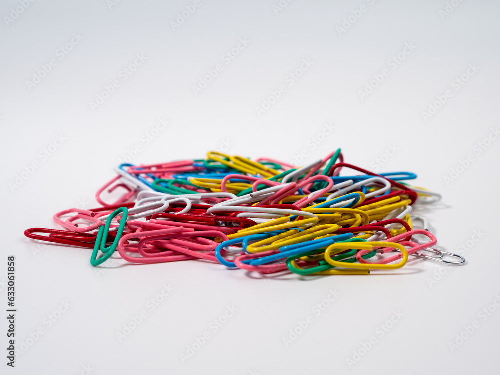 Multicolored paper clips on a white background. Colored paper clips close up.