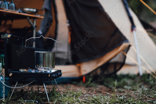 Boiling water in a pot on a portable gas camping stove. Preparing a meal outdoors near the tent on a camp ground. Nomad life traveling, simple slow living, summer escape adventure close to nature 