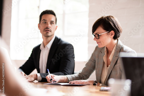 Businesswoman writing in notebook during meeting in office photo