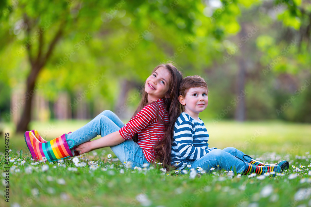 Φωτογραφία Happy kids boy and girl in rain rubber boots playing outside in the green park w