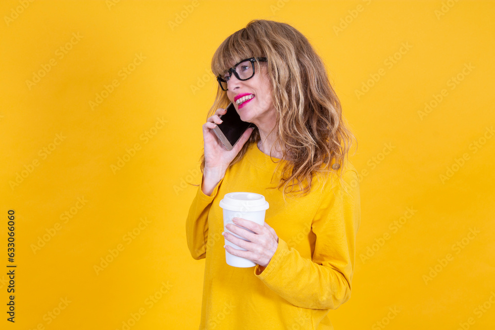 woman talking on smartphone and with takeaway drink on yellow background woman talking on smartphone and with takeaway drink on yellow background