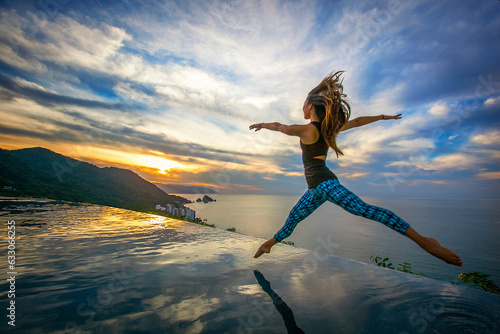 Young woman jumping into infinty pool photo