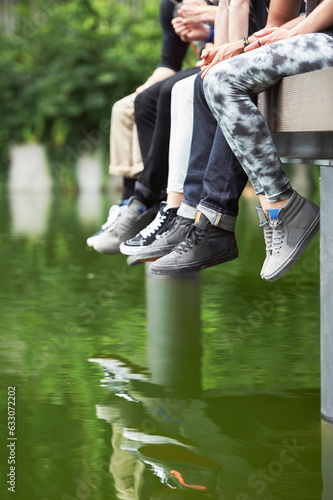 Feet of teenagers wearing sneakers on jetty photo