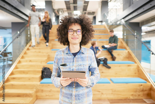Young businessman with tablet PC by office staircase