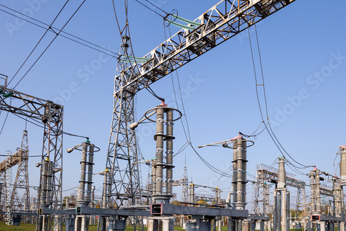 A high-voltage power electrical substation. Power lines, poles, ceramic and glass insulators, lightning arresters, sulfur hexafluoride circuit breakers, current transformers.