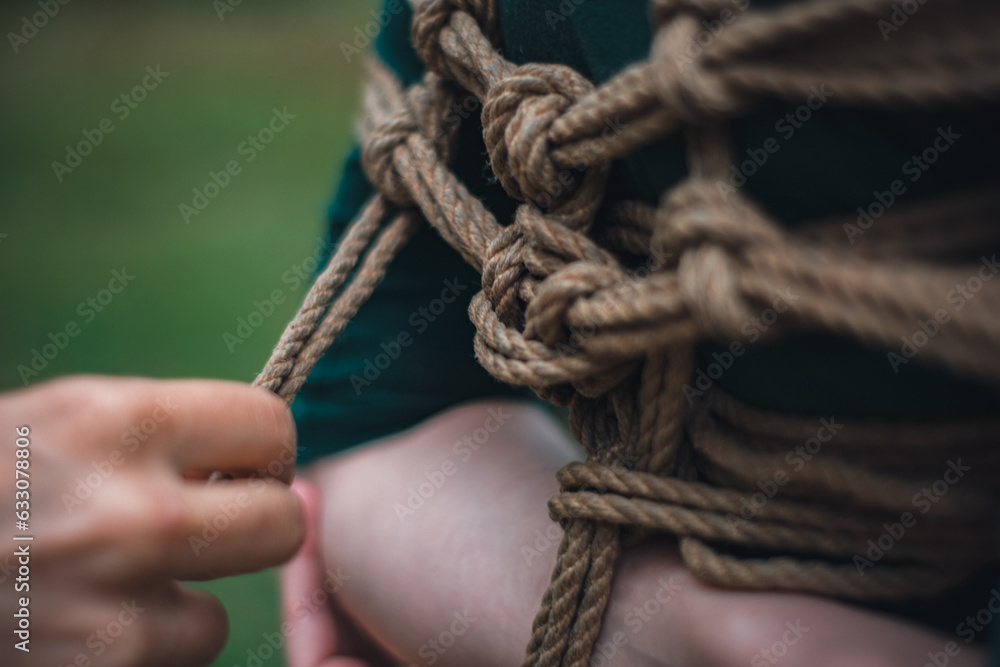Fototapeta premium a man ties up a woman in green body and black tights with a natural rope japanese art of aeshetic shibari bandage kinbaku 