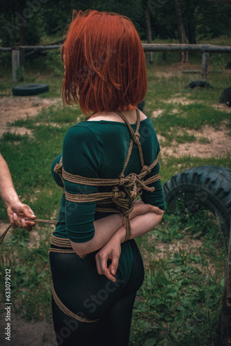 a man ties up a woman in green body and black tights with a natural rope japanese art of aeshetic shibari bandage kinbaku
