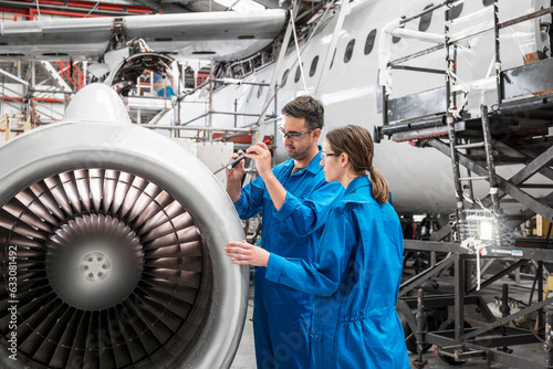 Man and woman working on airplane engine